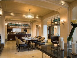 Ein eleganter Speisebereich mit einer Chandelierleuchtre, eine Bar mit Regalen voller Gläser und Blick in die Küche.