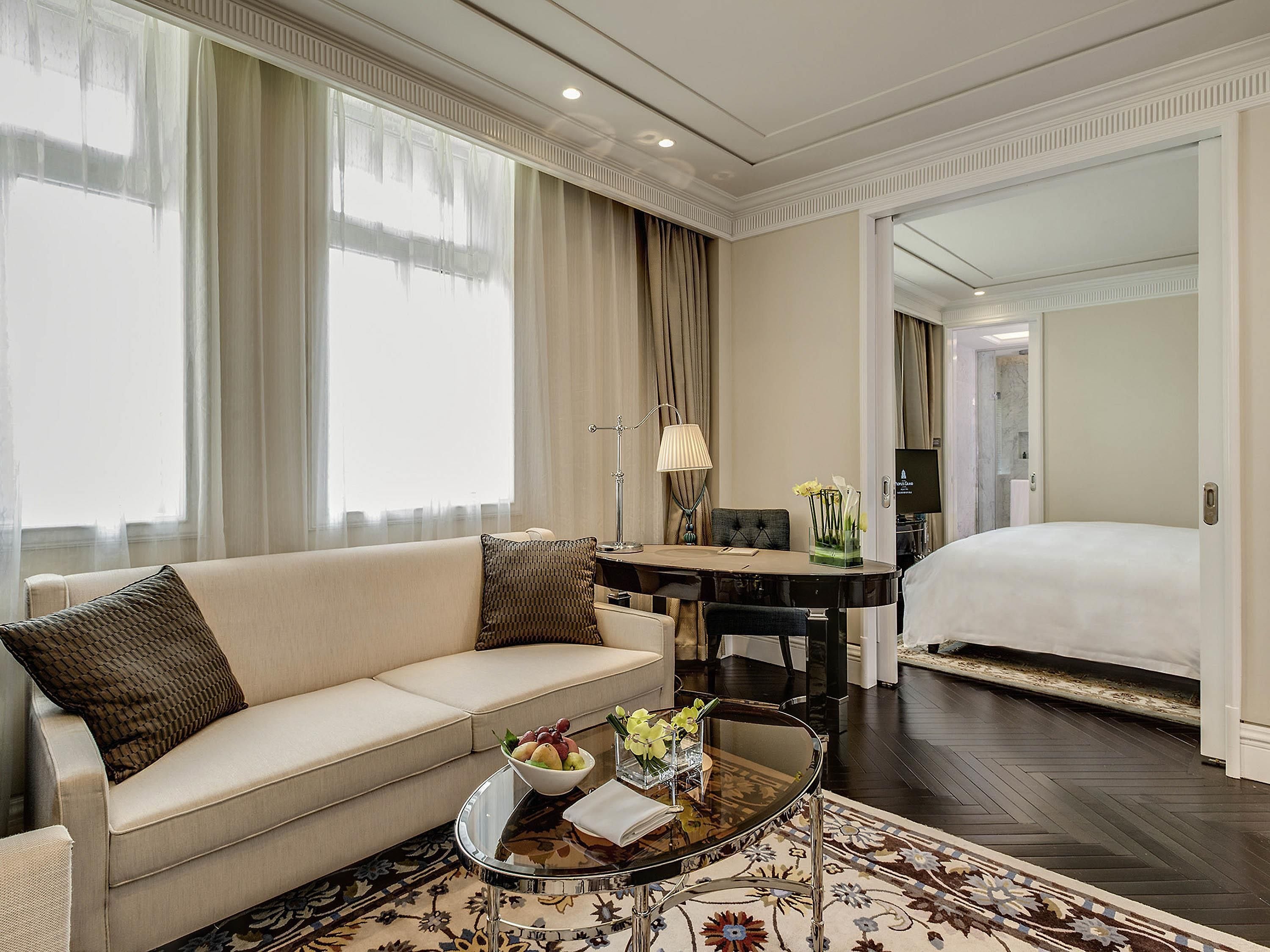 A hotel room with a sofa, a dining table, a TV, and a bed.