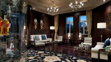 A luxurious living room with a dark wood-paneled wall, a large round carpet, and a glass display case with bottles.