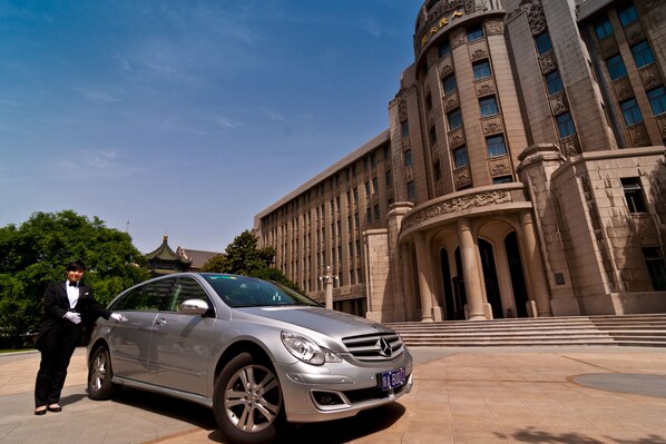 Un coche plateado estacionado frente a un edificio grande e histórico con columnas y una cúpula.