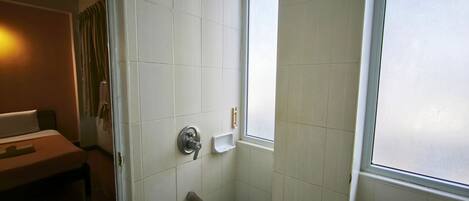 Un baño con ducha, inodoro, lavabo y ventana.