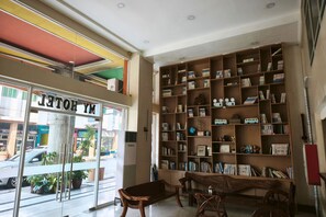 A hotel lobby with a large bookshelf, a bench, and a view of the street outside. - My Hotel Davao City (Davao)