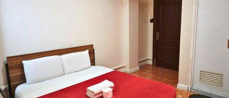 Una habitación de hotel con una cama, un armario y una puerta.