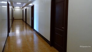 A long, narrow hallway with wooden doors on one side and a tiled floor. - My Hotel (Davao)