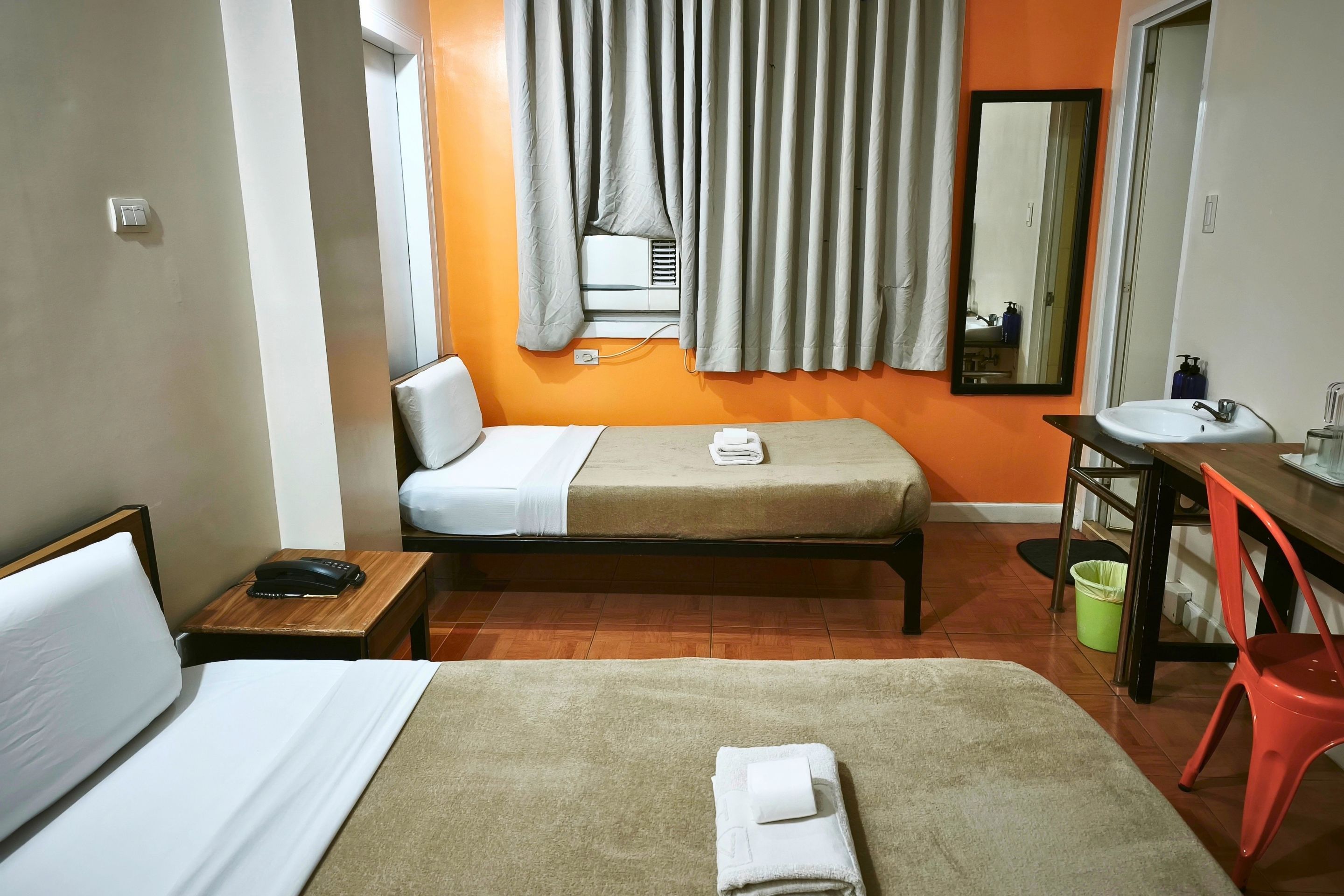 Une chambre d’hôtel comprenant un lit, une table de chevet avec un téléphone, un bureau avec un lavabo et un miroir.