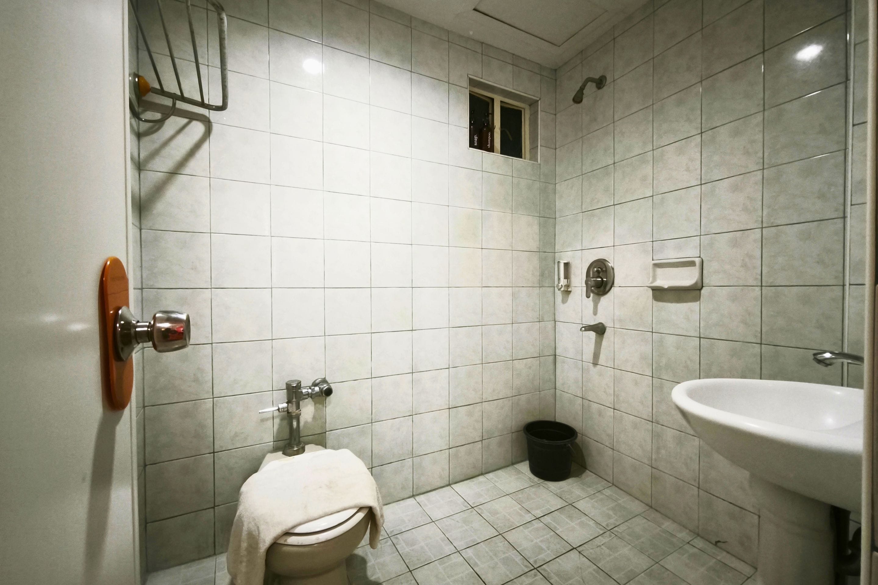 Ein kleines Badezimmer mit Fliesen, ausgestattet mit Toilette, Waschbecken und Dusche.