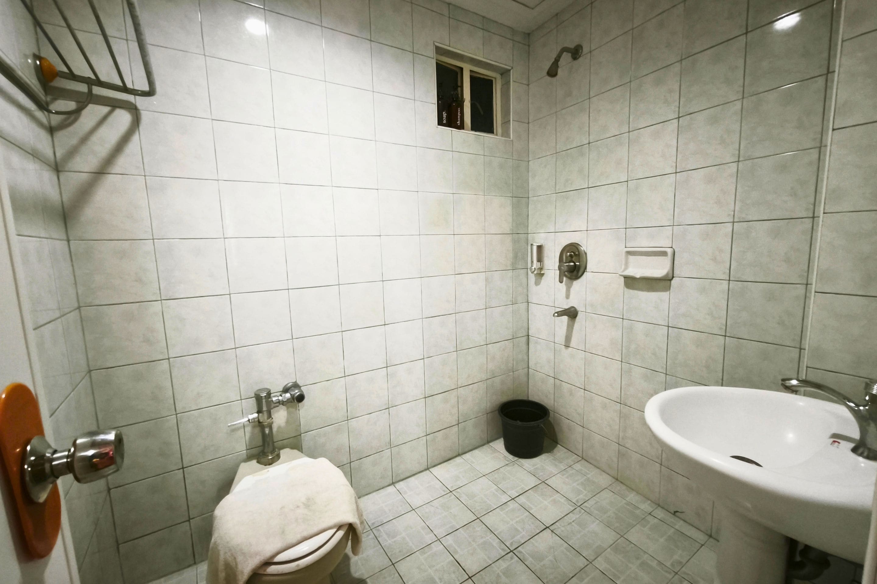 A bathroom with a toilet, sink, and a small window.