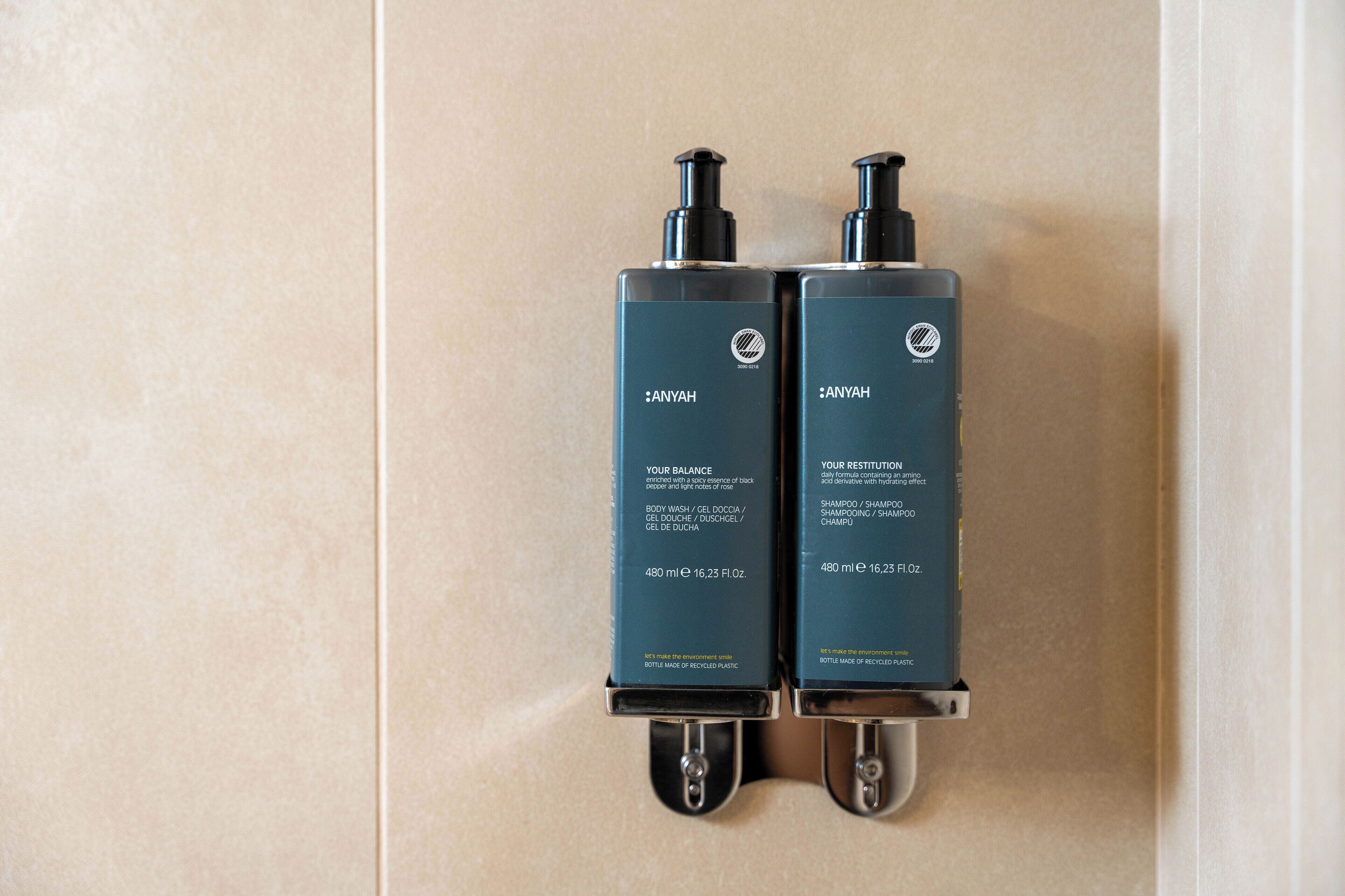Two black bottles of Anyah shampoo and conditioner mounted on a wall.
