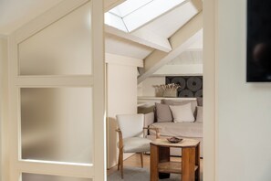 A modern, well-lit room with a skylight, a comfortable sofa, a wooden table, and a chair. - Hotel 900 (Giulianova)