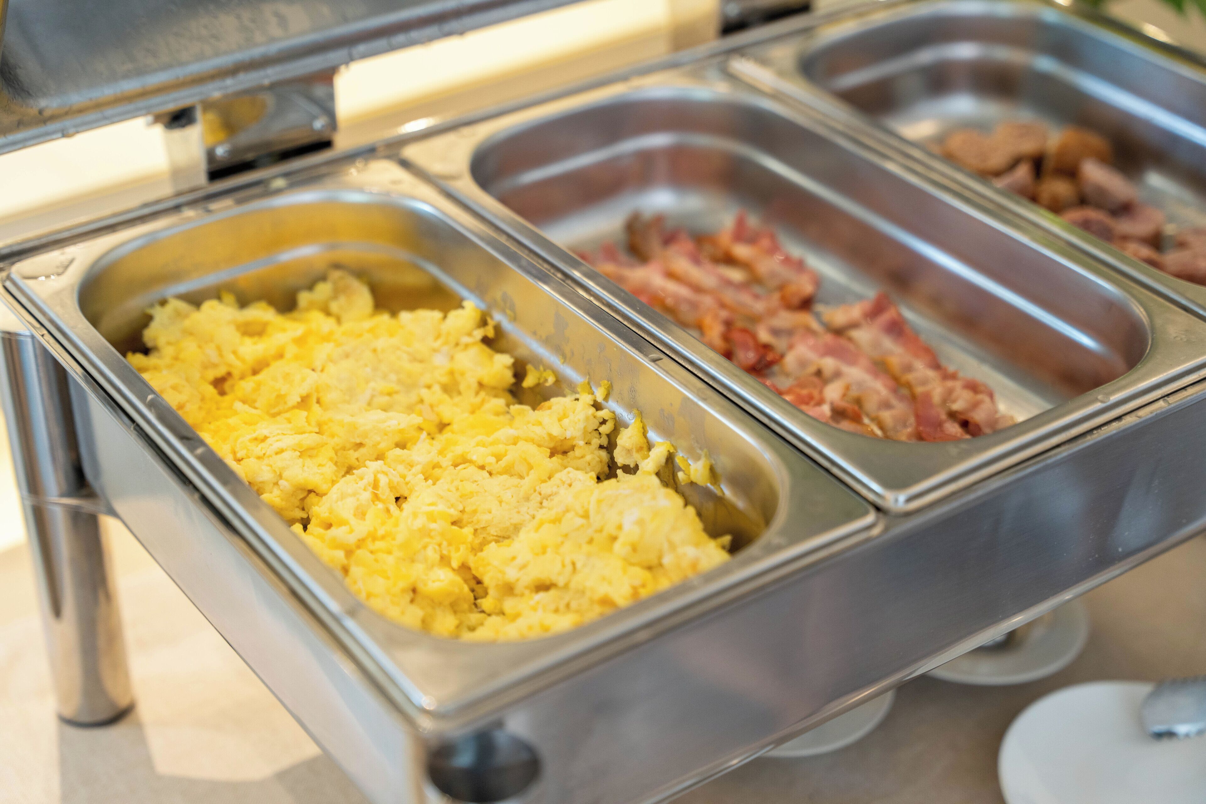 A buffet with scrambled eggs and bacon.