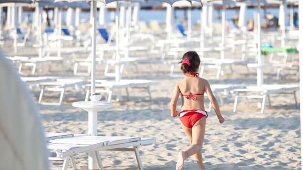 A beach with rows of white lounge chairs and umbrellas, a sandy beach, and a clear view of the sea. - Hotel 900 (Giulianova)