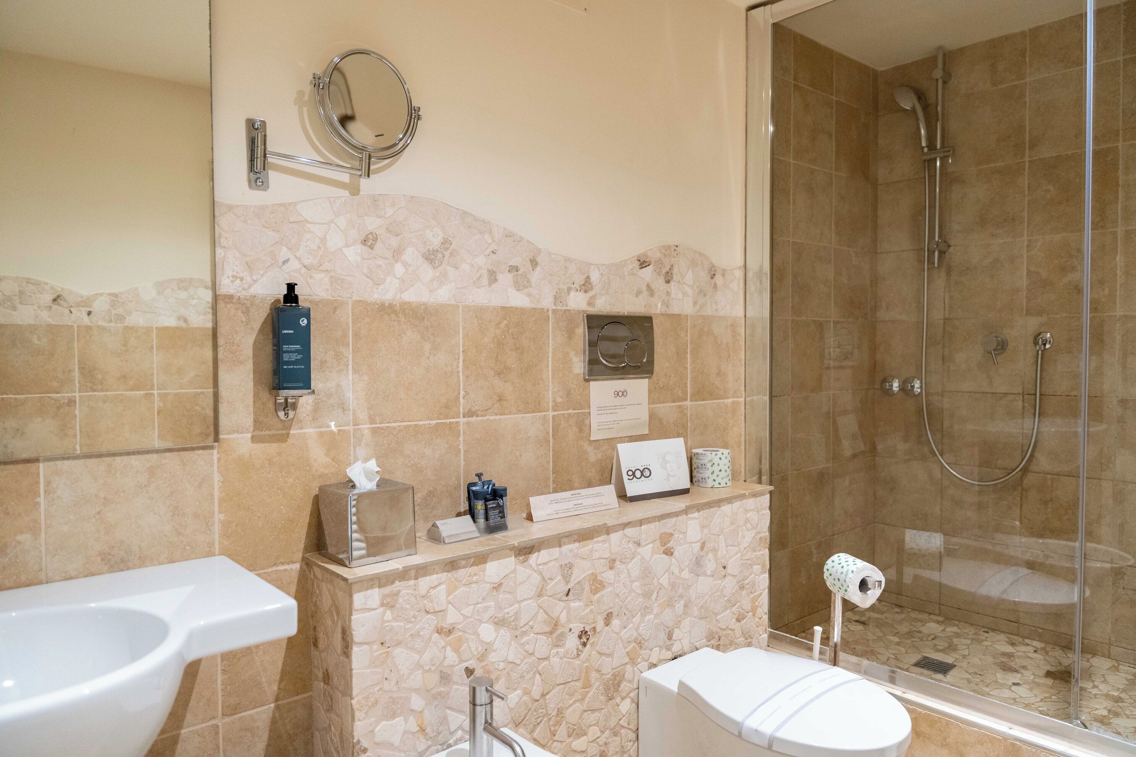 Ein Badezimmer mit Toilette, Bidet und Dusche. Es sind Pflegeprodukte an der Wand und ein Handtuchhalter vorhanden.