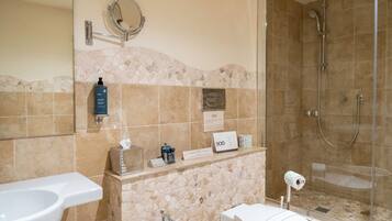 Ein Badezimmer mit Toilette, Bidet und Dusche. Es sind Pflegeprodukte an der Wand und ein Handtuchhalter vorhanden.