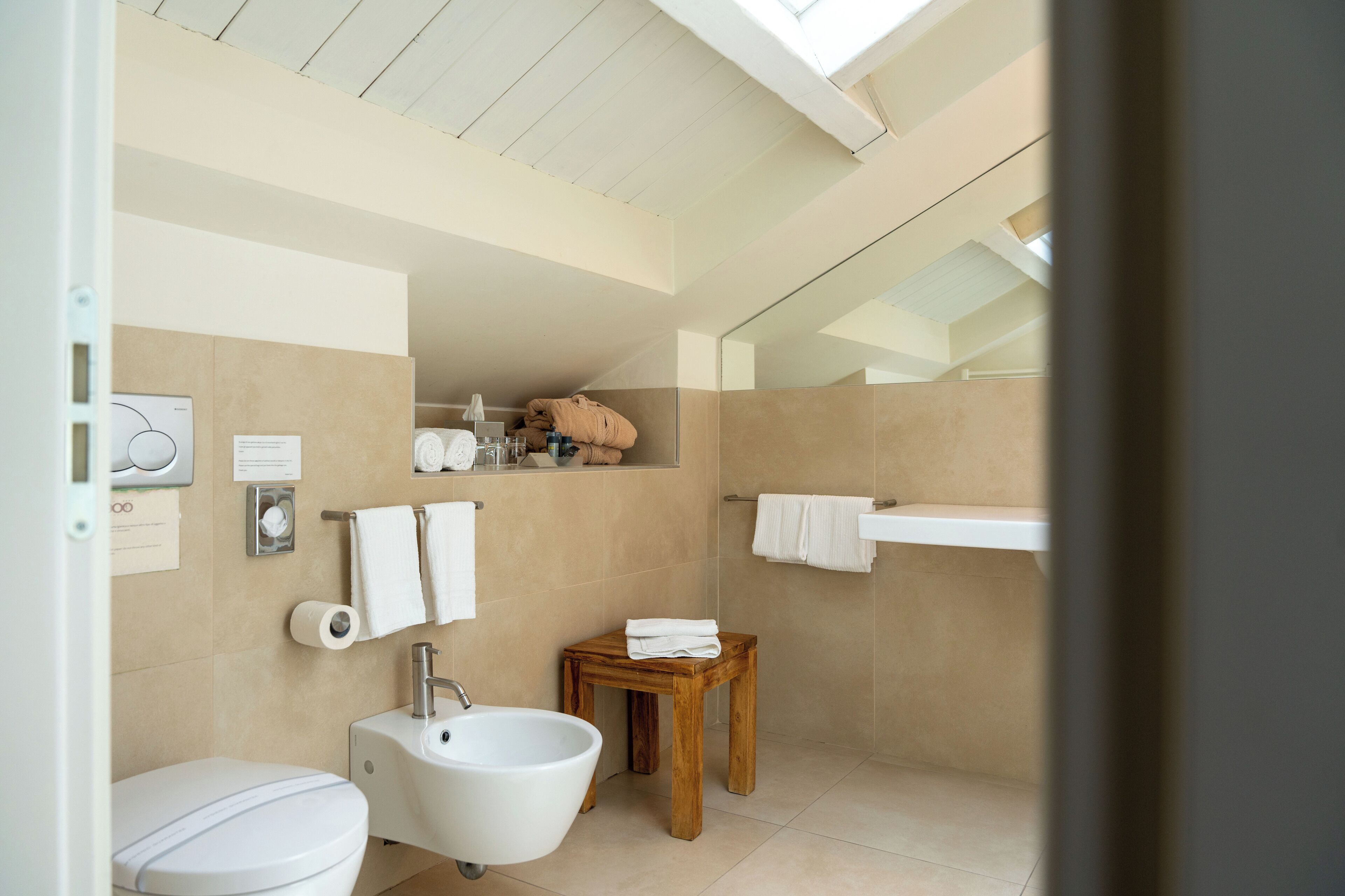 Un baño moderno con inodoro, lavabo y taburete de madera.