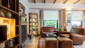 A cozy living room with a fireplace, leather sofas, and a bookshelf. - Hotel 900 (Giulianova)
