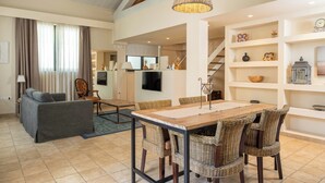 A spacious living area with a dining table, wicker chairs, a sofa, and a staircase leading to another level. - Hotel 900 (Giulianova)
