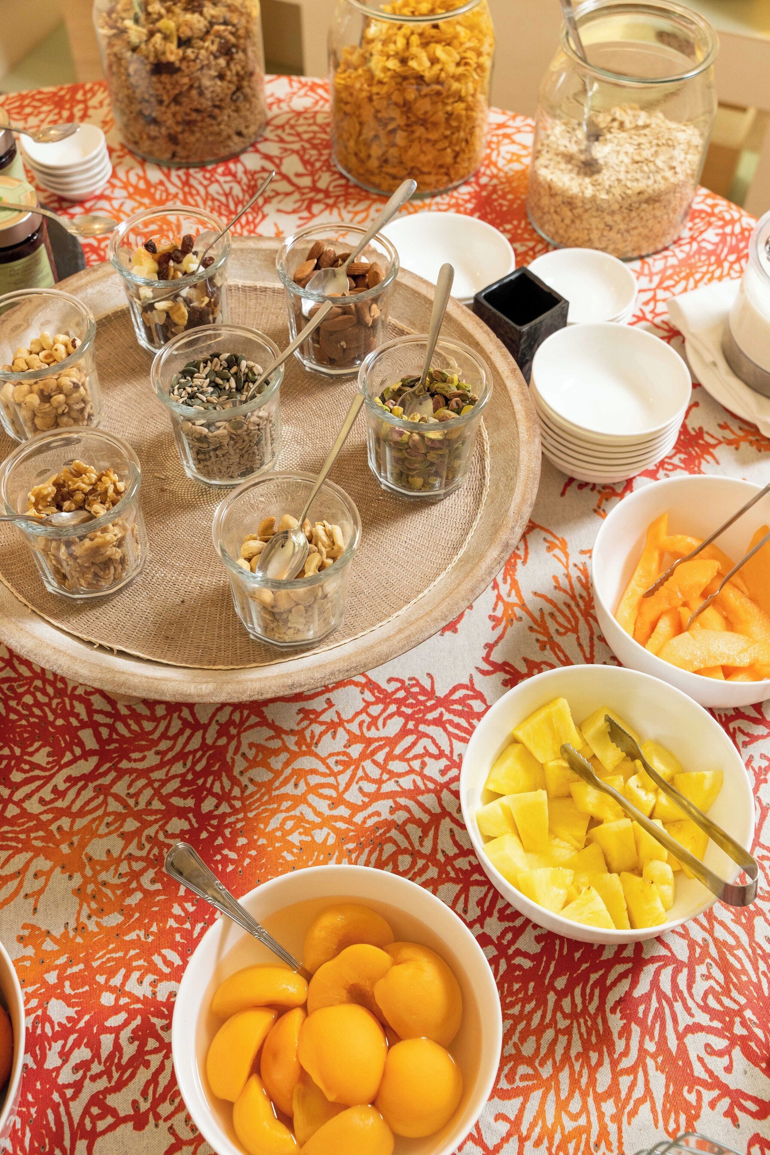 A table with various food items and containers, including bowls of fruit and jars of nuts.
