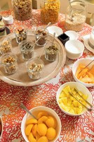 Una mesa con diversos alimentos y recipientes, incluyendo tazones de fruta y tarros de nueces.