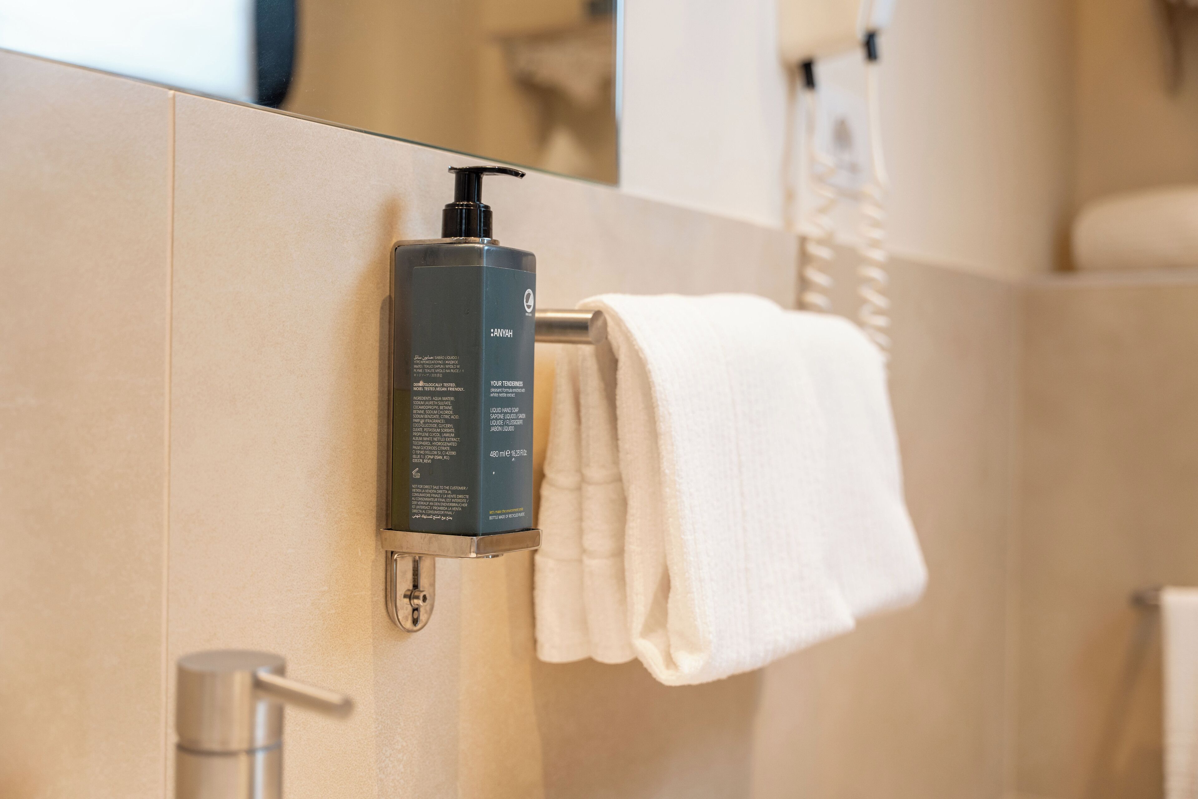 Un bagno con un dispenser di sapone montato sulla parete, un asciugamano su un portasciuga e una zona doccia.