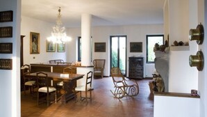 A spacious dining area with a wooden table and chairs, a chandelier, and framed artwork on the walls. - Bed and Breakfast Casa Nini (Lierna)