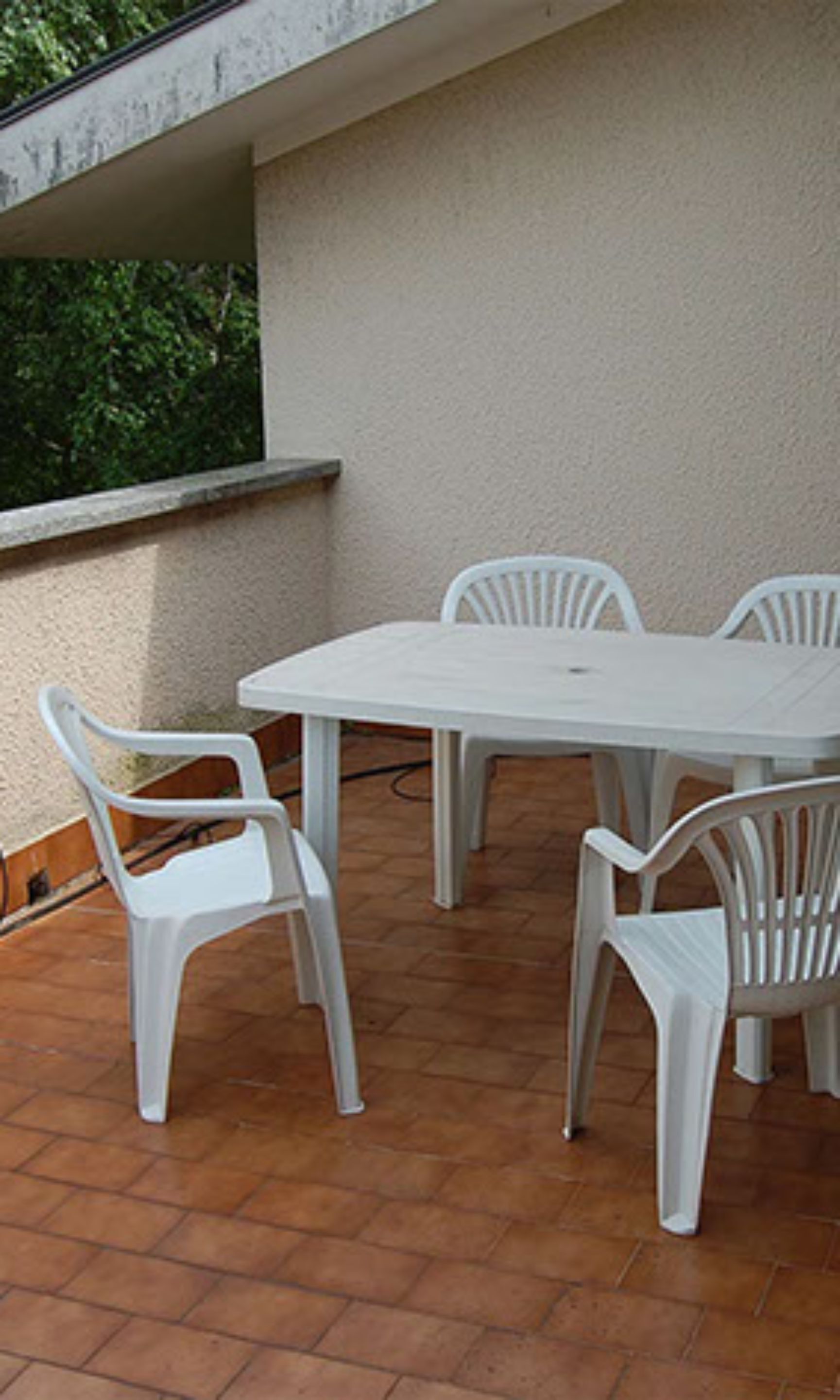 A patio area with a white table and four white chairs.