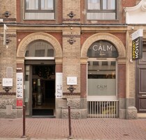 Entrada de un hotel con un cartel que dice 'CALM HOTEL' y otro cartel que indica '2, Rue des Buxes'.
