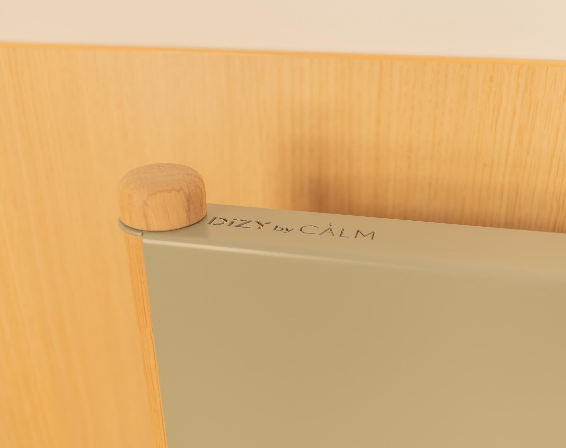 A wooden object with 'DIZY by CALM' engraved on a light-colored surface.