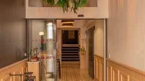 A hallway with patterned flooring, a bicycle, and a hanging floral arrangement. - CALM Appart' & Hostel (Lille)