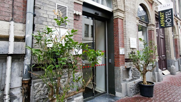 A brick building with a glass door entrance, a sign for the "Appart Hotel," and potted plants in front. - CALM Appart' & Hostel (Lille)