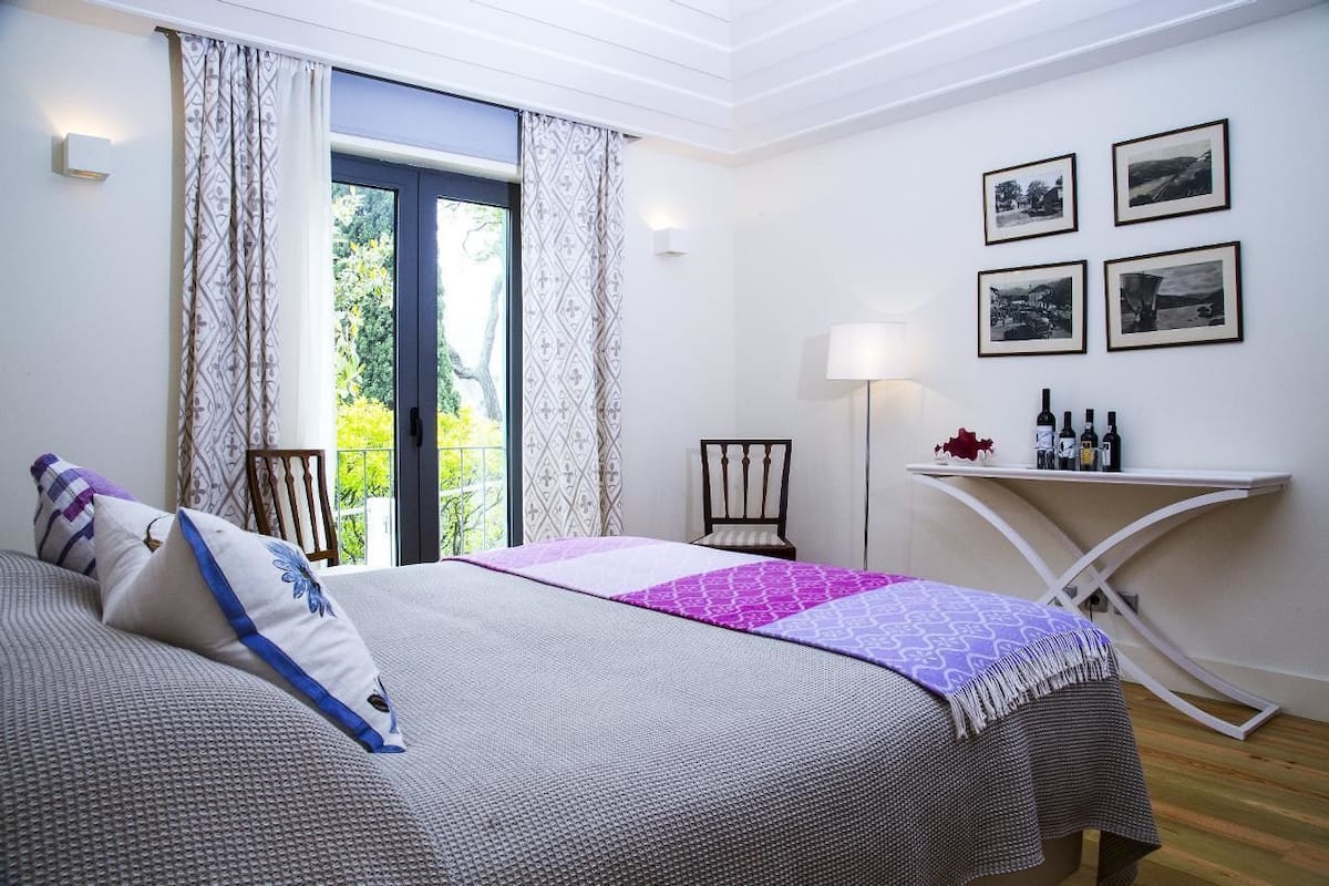 A bedroom with a bed, a desk, and a chair. There are four framed pictures on the wall.