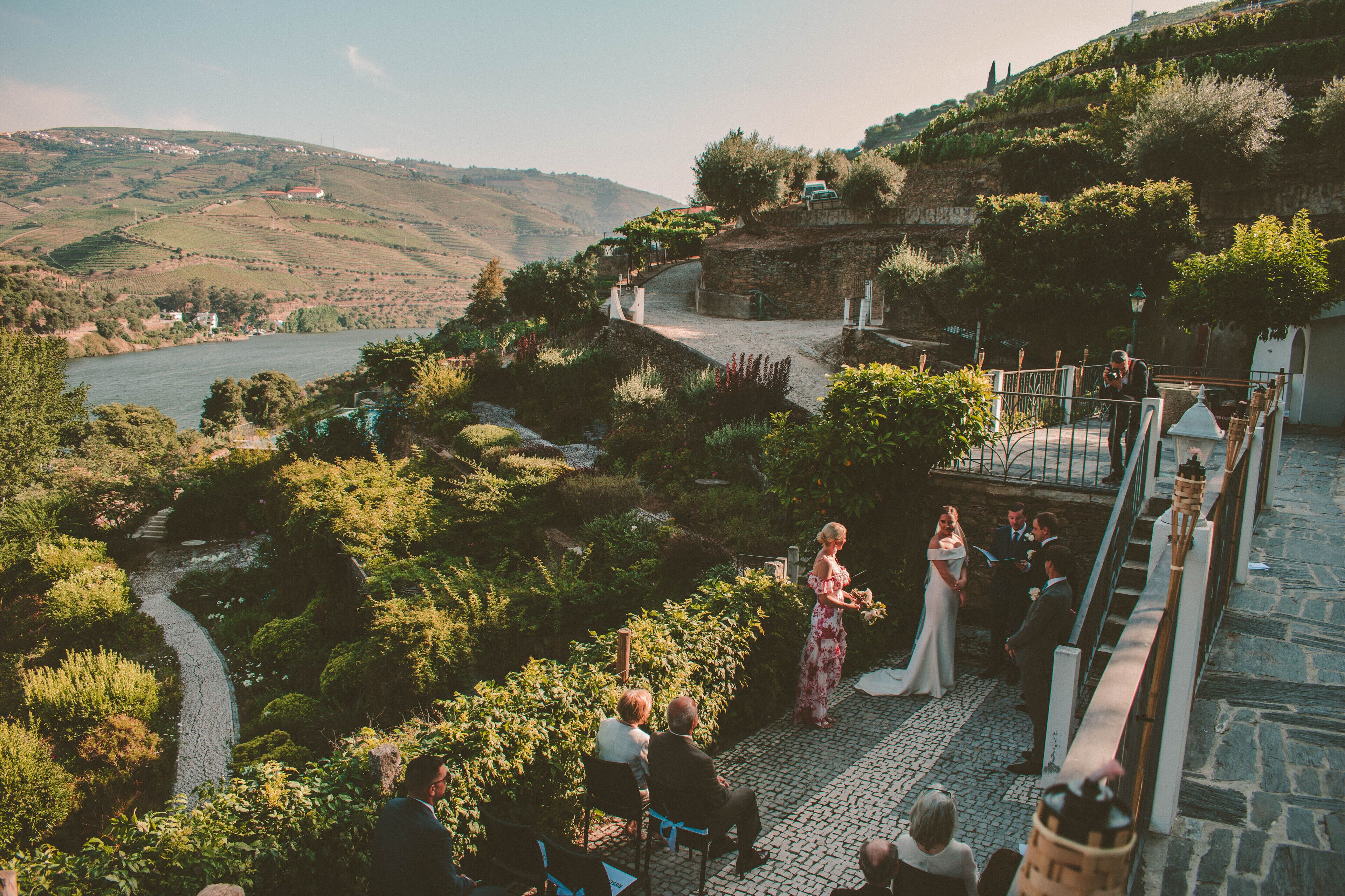 A wedding ceremony outdoors with a scenic view of hills and a river.
