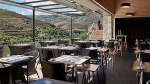 An outdoor dining area with tables and chairs, overlooking a scenic landscape.
