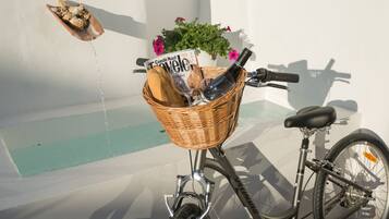 Un vélo muni d’un panier contenant un magazine, une bouteille et une miche de pain.