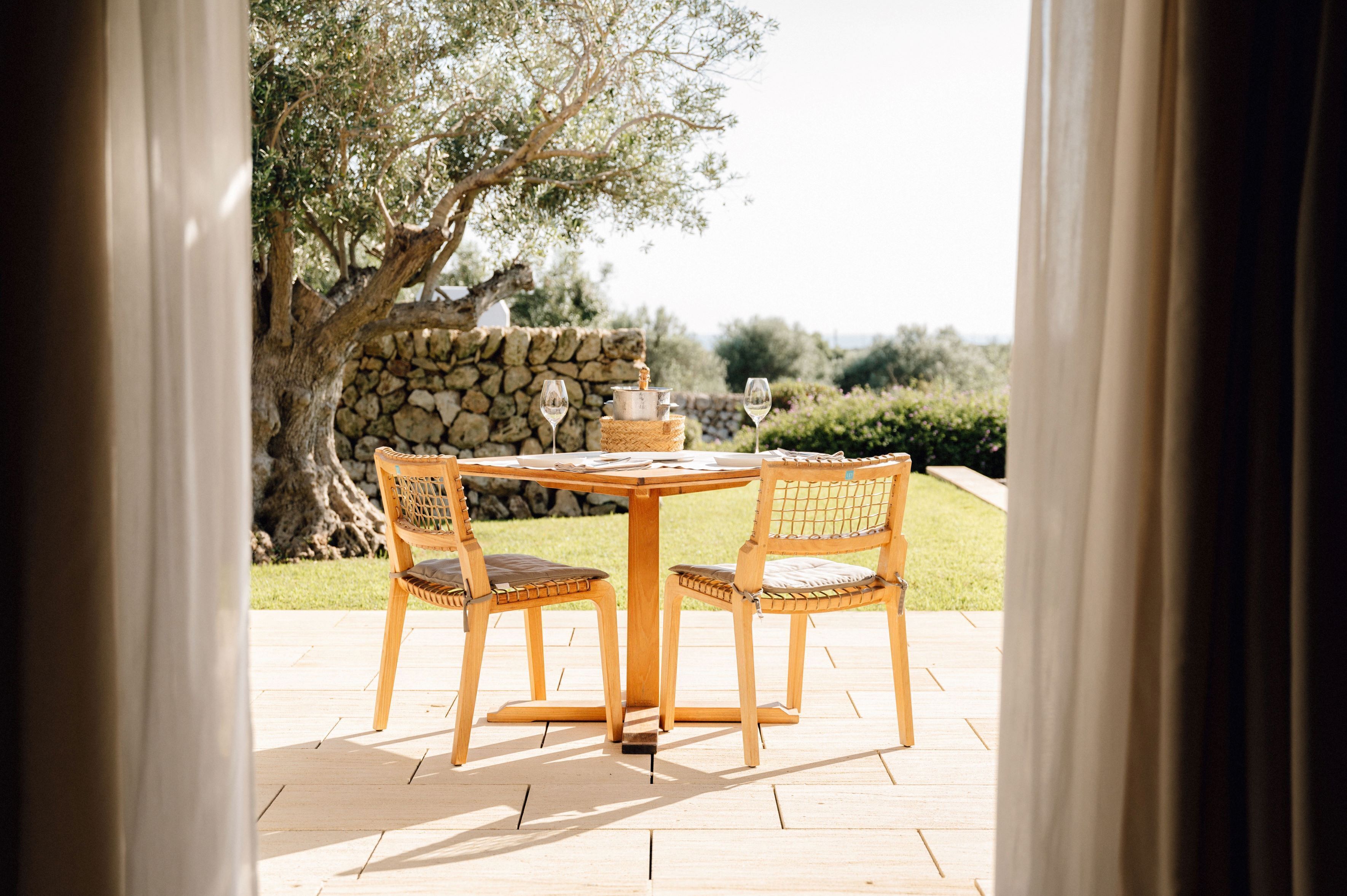 An outdoor patio with a round wooden table and four wicker chairs.