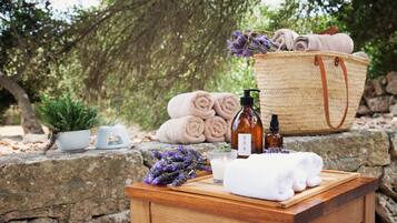 A wooden table with a bottle, a candle, and a towel.