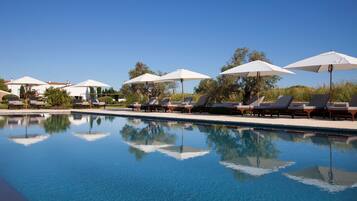 Una piscina al aire libre, sombrillas, tumbonas