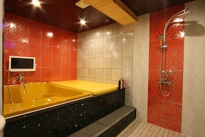 A bathroom with a yellow bathtub, a shower, and a tiled wall with a red pattern. - ON Motel Haeundae (Busan)