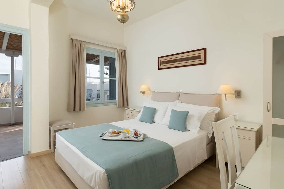 A neatly arranged bedroom with a bed, bedside tables, a window with curtains, and a breakfast tray on the bed.