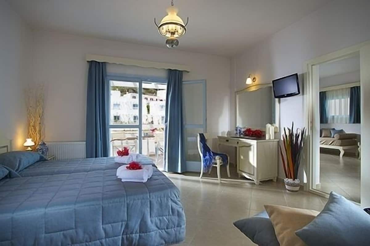A hotel room with a large bed, a desk, a chair, a television, and a view of the outside.