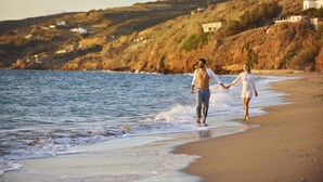 A beach scene with a couple walking hand in hand along the shore. - Perigiali Hotel (Skiros)