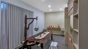 Altar table with a brass bowl, statue, and candle, set against a neutral backdrop.