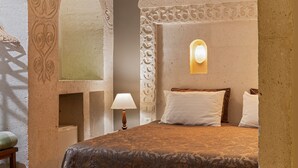 Un dormitorio con cama, almohadas, una lámpara y una mesita.