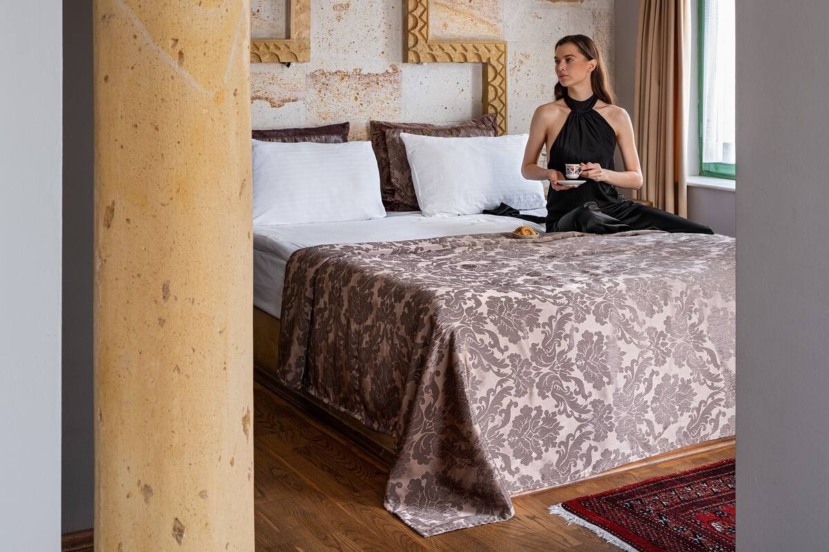 A room with a bed, a window with curtains, and a decorative archway.