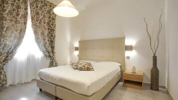 Un dormitorio con cama, mesita de noche, lámpara y un florero.