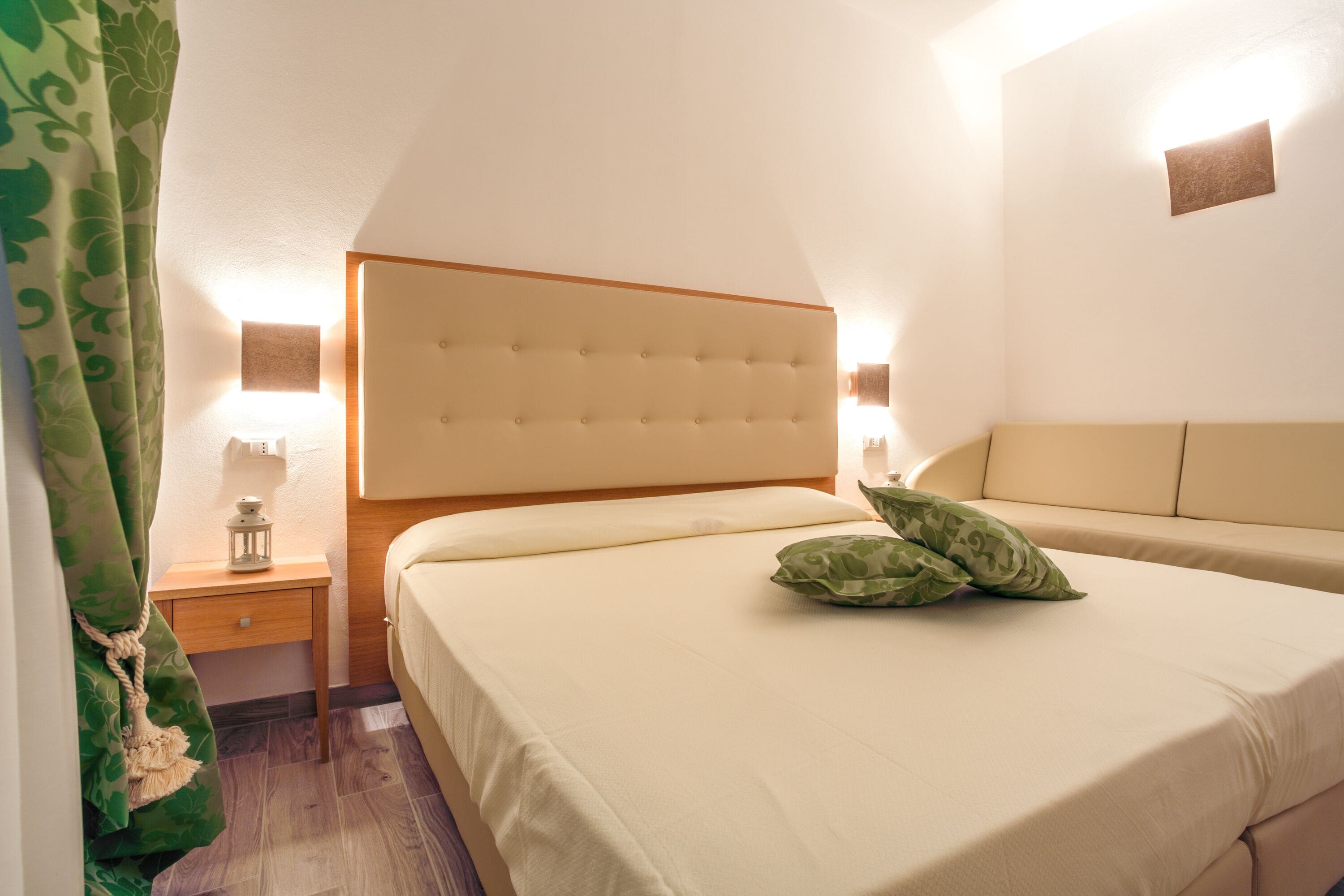 A bedroom with a large bed, a nightstand, a lamp, and a wall-mounted light.