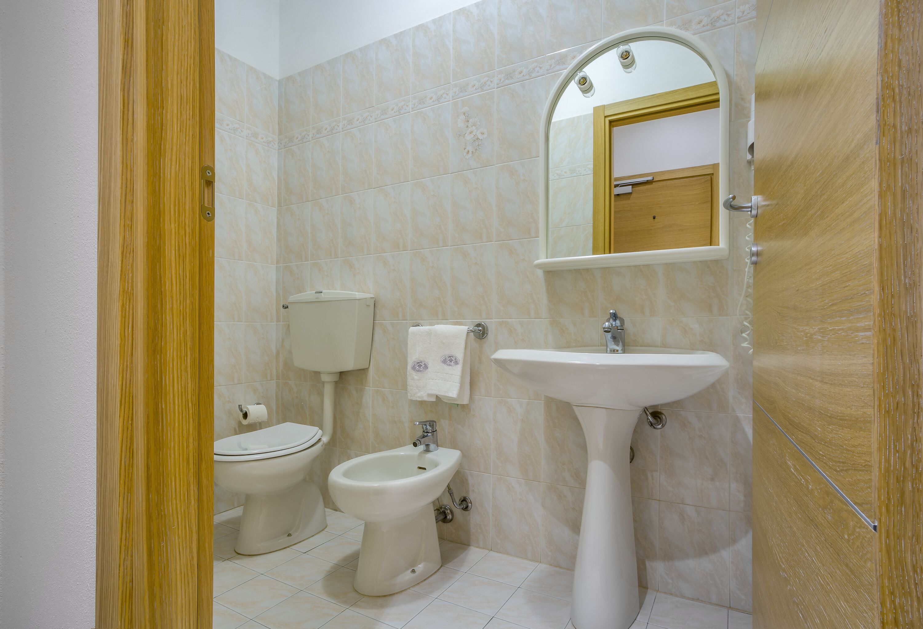 A bathroom with a toilet, bidet, and sink.