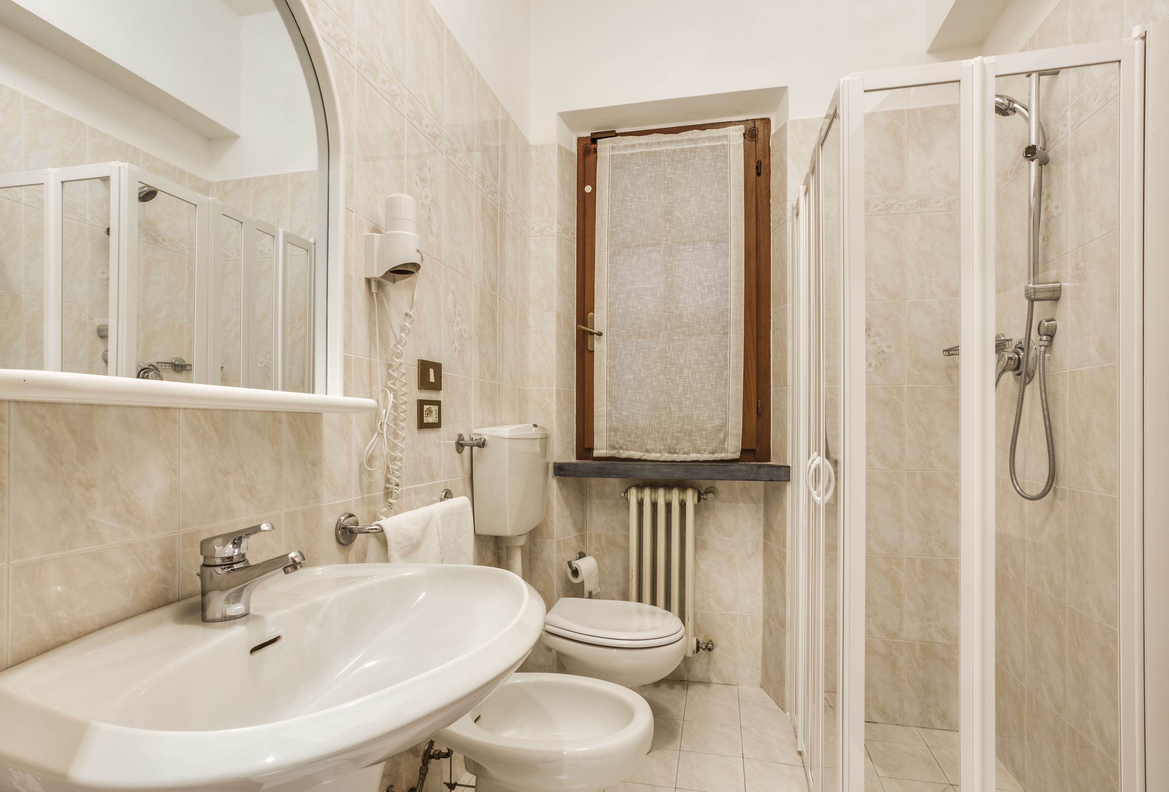 A bathroom with a sink, toilet, shower, and a towel rack.
