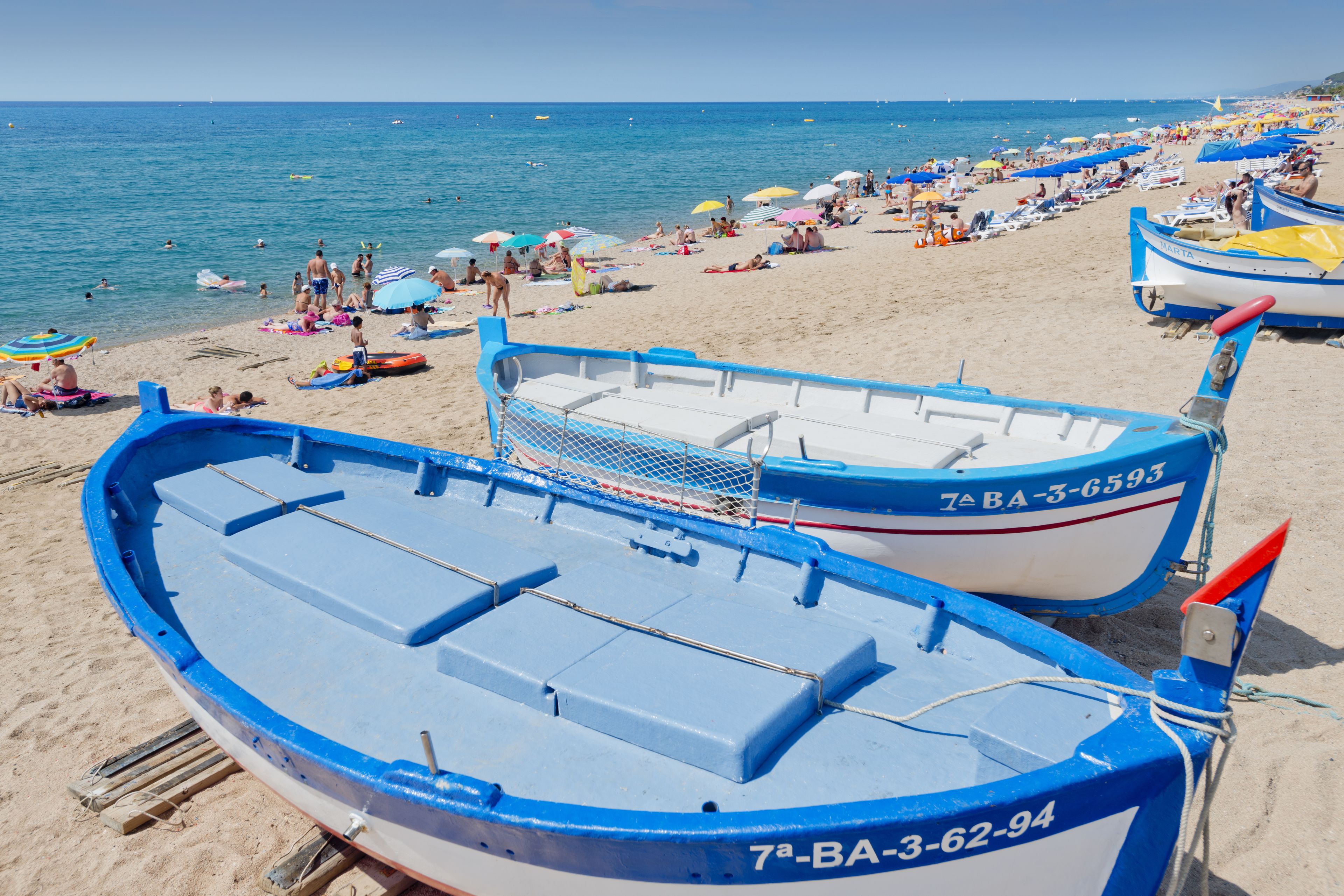 Una playa con barcos y gente.