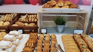 Une vitrine de boulangerie présentant une variété de produits de boulangerie, notamment du pain, des viennoiseries et des gâteaux.