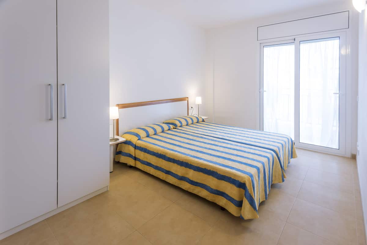 A bedroom with a bed, bedside tables, and a sliding glass door.